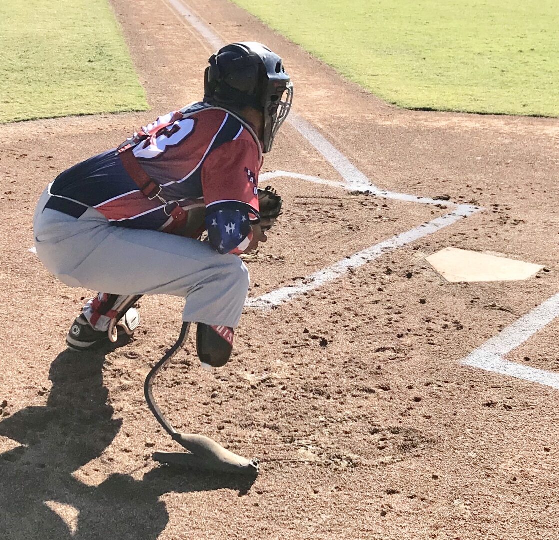 A baseball player is crouching down to catch the ball.
