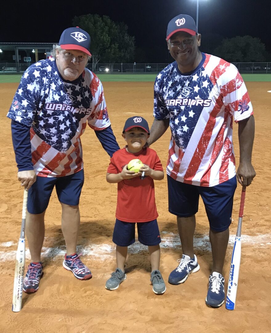 Two Men Holding Baseball Bats While a Boy Holds Ball