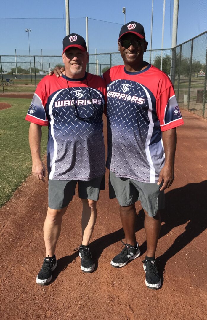 Two men standing next to each other on a baseball field.