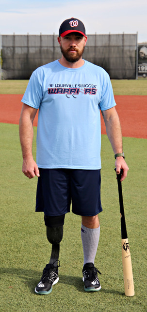 A man in blue shirt holding baseball bat on field.