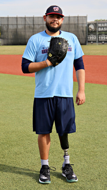 A man in blue shirt and shorts holding a baseball mitt.