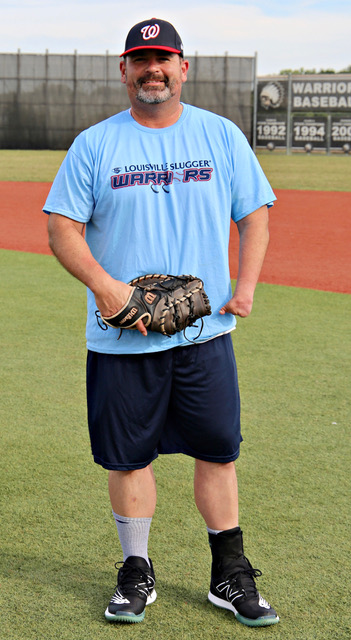 A man in blue shirt holding a baseball mitt.