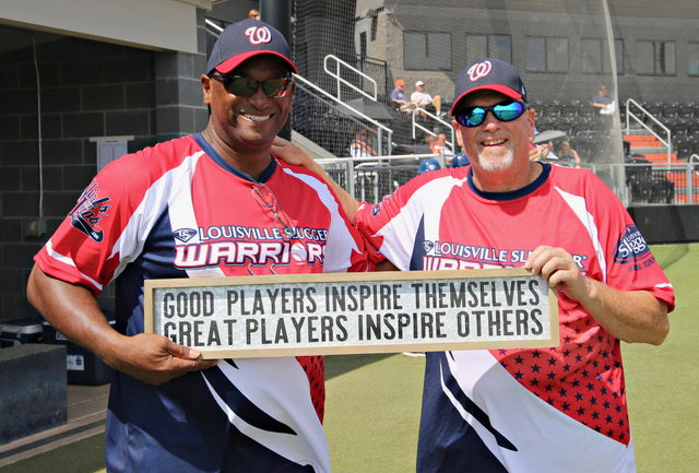 Two men holding a sign that says " good players inspire themselves great players inspire others ".