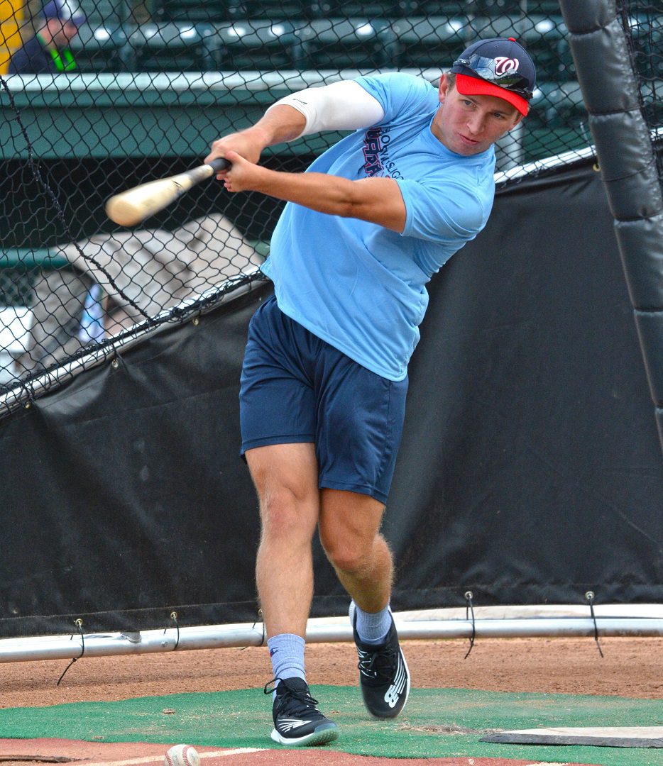 A man swinging a baseball bat on top of a field.