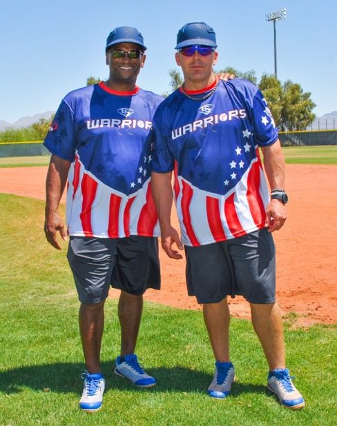 Two men standing on a baseball field wearing patriotic shirts.